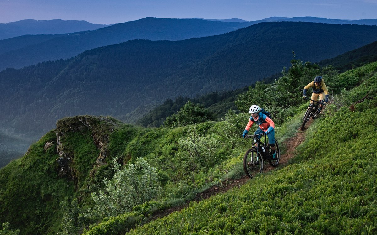 two riders on a trail in the grassy mountains