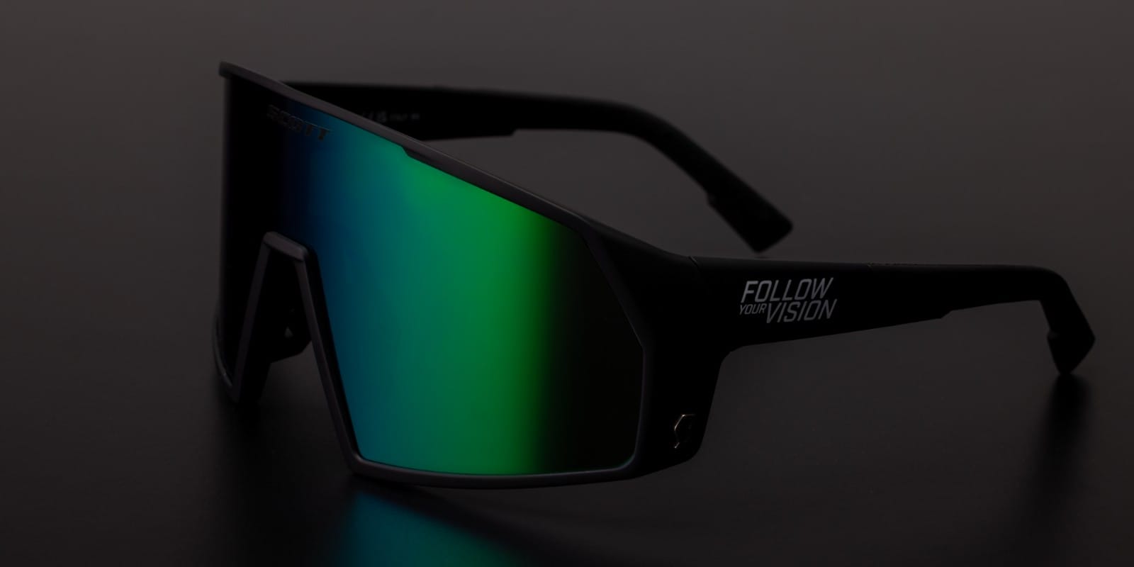 SCOTT Pro shield follow your vision sunglasses beauty shot, on a dark background, showing a blue to green reflect on the lens
