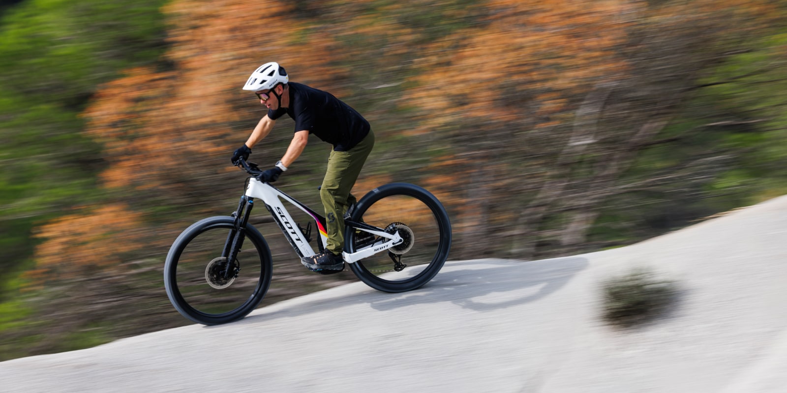 guy on a white patron, with a white helmet, going super fast on a white rocky ridge