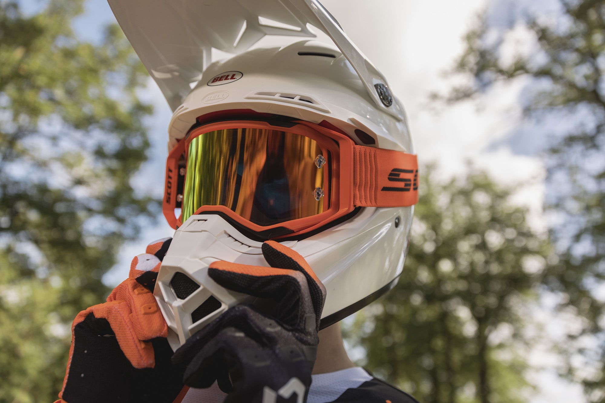 rider with orange goggle and gloves, adjusting his white helmet