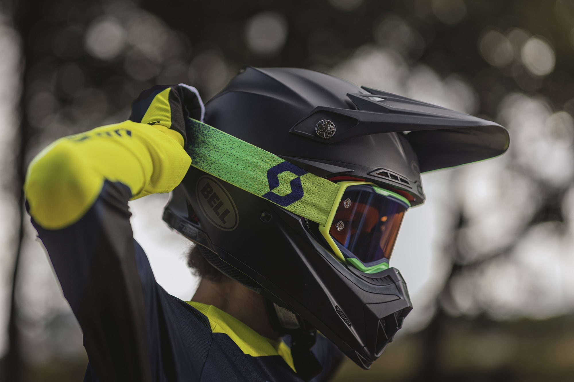 rider adjusting his yellow and green goggle over his black helmet