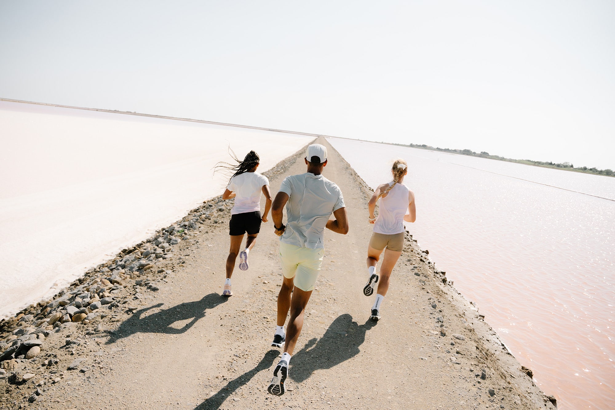 Three runners on a winding gravel trail through a pine forest, wearing SCOTT Sports gear and Pursuit Gravel running shoes, showcasing the outdoor running experience.