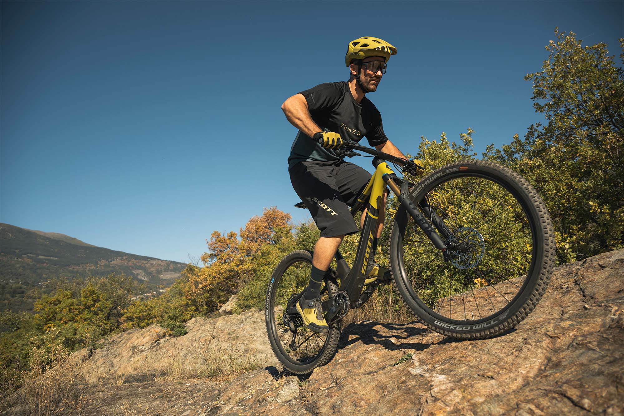 A man riding a Scott mountain bike on a trail on a sunny day